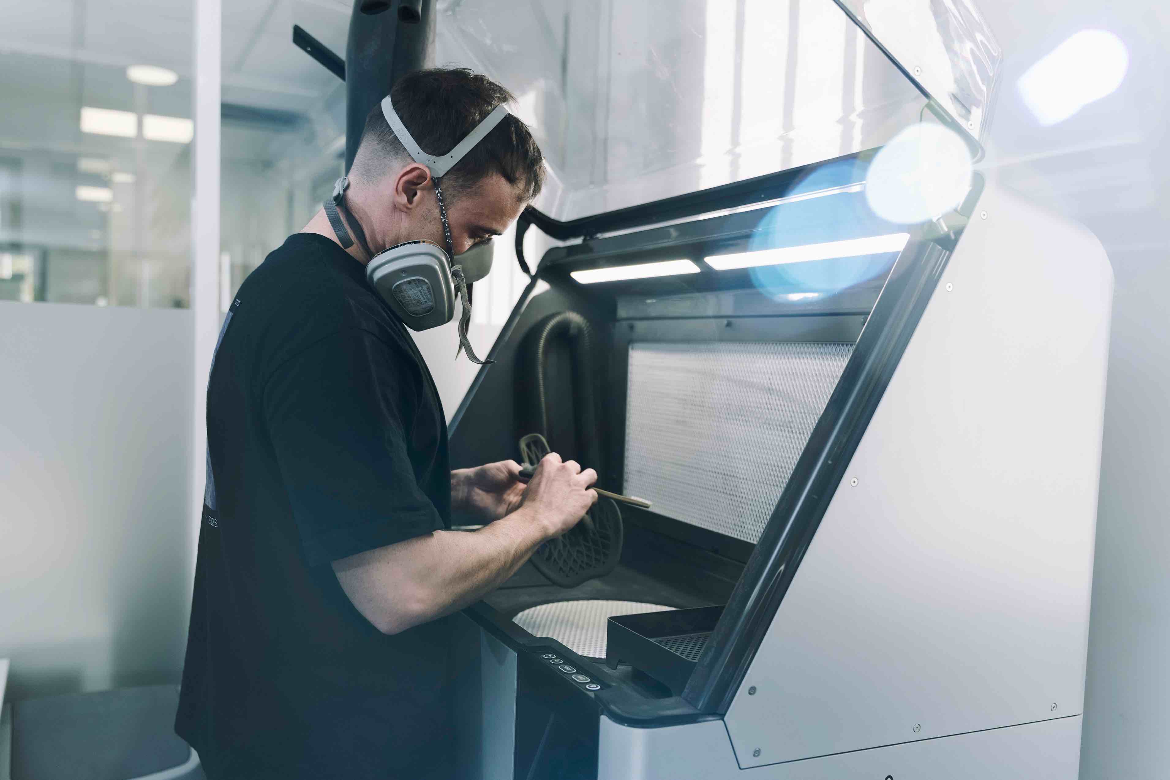 Quentin Cardeur, fondateur d'Arche réalisant un dépoudrage d'une pièce mécanique créée en impression 3D